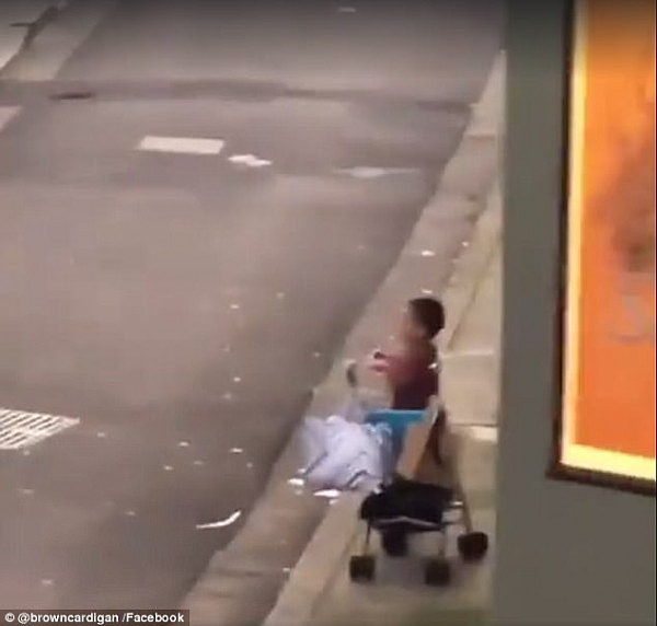 A young boy was seen standing on his pram holding up a phone to take pictures of his mother