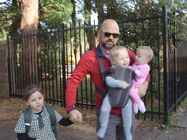 Anthony juggling his twins and older daughter Asha during the school drop off.