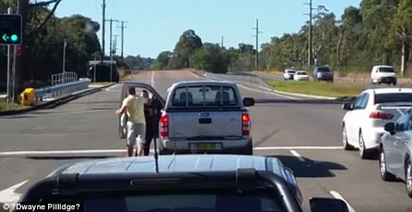 The man strikes the woman directly in the face, snapping her head backwards, and then calmly walks back to his ute