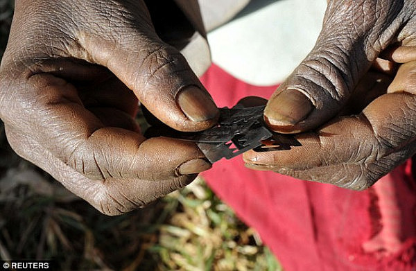 An immigrant couple who police claim tried to take their newborn daughter overseas to be genitally mutilated have been banned from leaving Australia (pictured: a traditional surgeon holds razor blades before carrying out female genital mutilation)