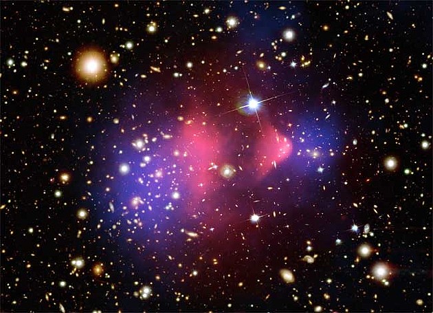 子弹星系团（Bullet Cluster）的合成图像。子弹星系团由一对迎面碰撞的星系团组成，得到了广泛的研究，并被认为是暗物质存在的有力证据。其中一个星系团穿过另一个，就像子弹穿过苹果一样，可能显示出暗物质（蓝色）与炽热气体（粉色）分离的明显迹象。