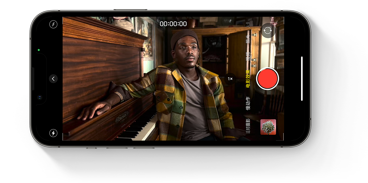 iPhone 屏幕上显示了处于电影效果视频模式的“相机”App，屏幕中有一个人坐在钢琴前