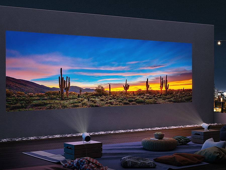 两台三星随享智能投影仪被分别放置在相邻的底座上，将沙漠的一个图像传送到白墙上，形成一个长达170 英寸的大屏幕。