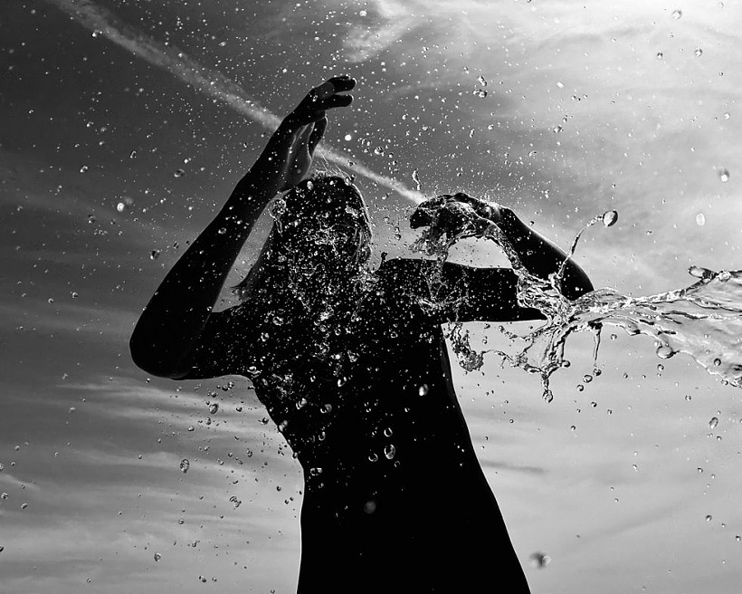 在这张使用 iPhone 拍摄的黑白照片中，水滴从一个人的剪影上落下。
