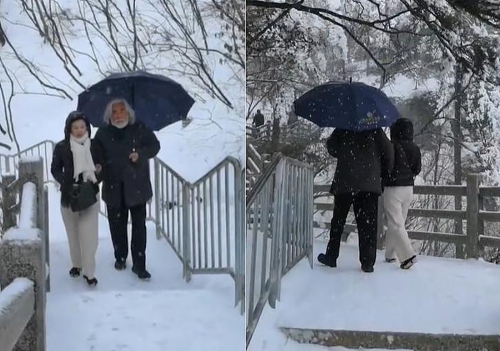 70 岁导演张纪中携娇妻赏雪 为妻子撑伞驻足拍照 - 1