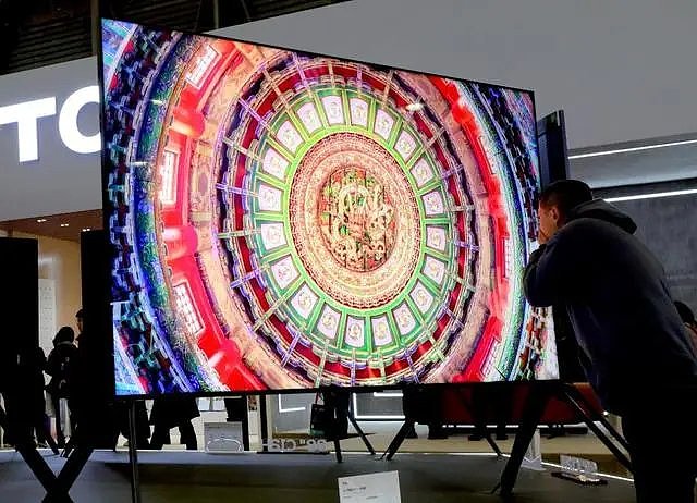 3月14日，在上海举办的2024年中国家电及消费电子博览会期间，参观者近距离观察一款电视展品的屏幕。（新华社）